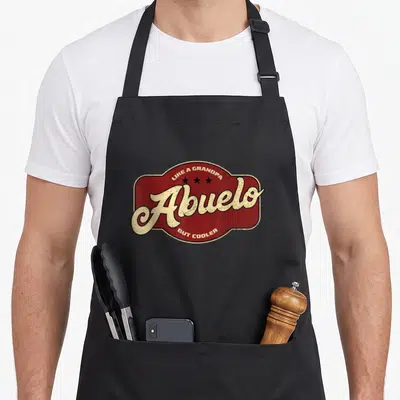 Abuelo grandpa apron - Retro red badge with Abuelo script and three black stars — shown on a black cotton canvas apron against a white background