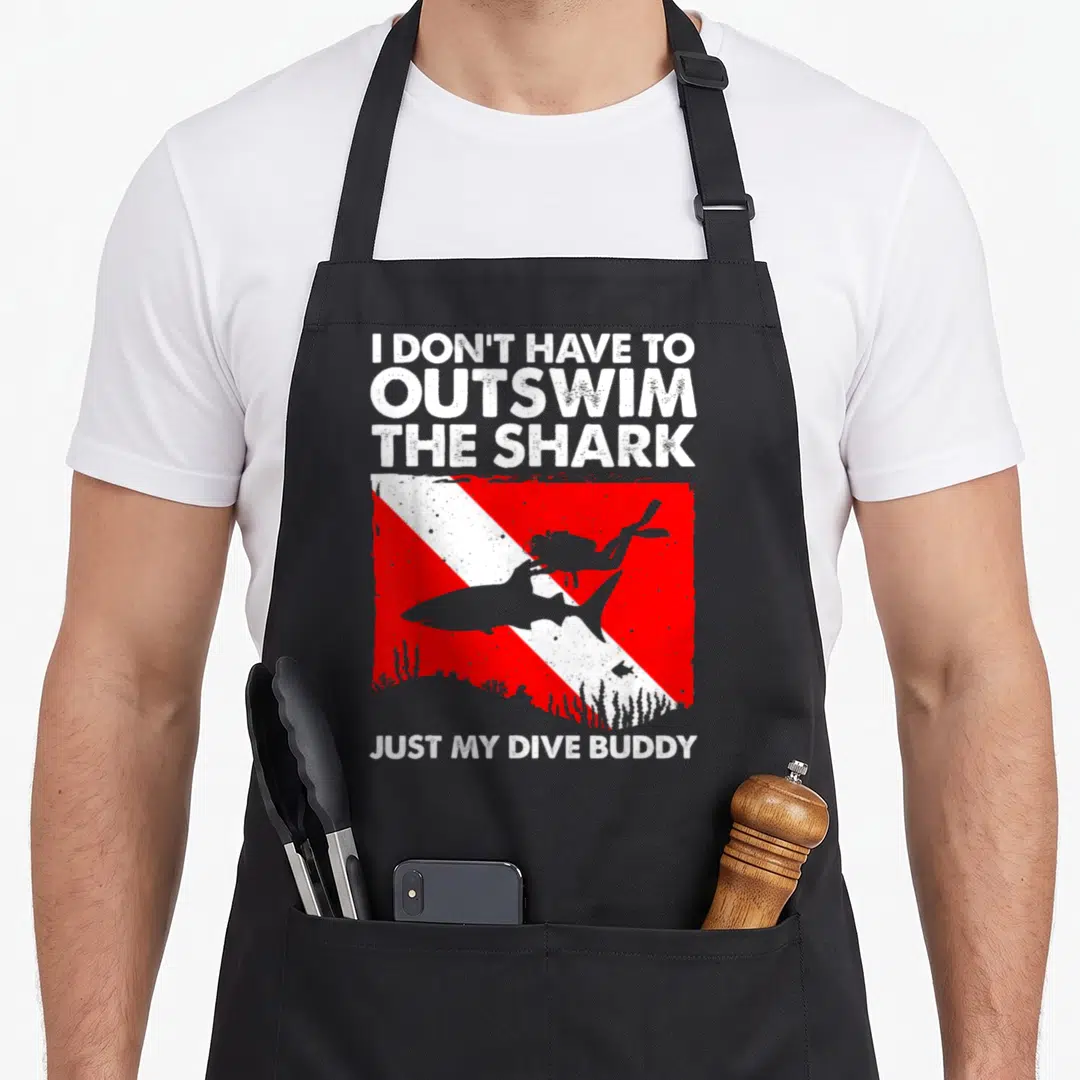 Scuba buddy aprons - I DON'T HAVE TO OUTSWIM THE SHARK text with red white striped diver flag and grey shark silhouette — shown on a black cotton canvas apron against a white background