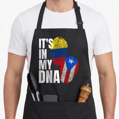 Colombian heritage aprons - IT'S IN MY DNA text next to two fingerprints with flag patterns — shown on a black cotton canvas apron against a white background