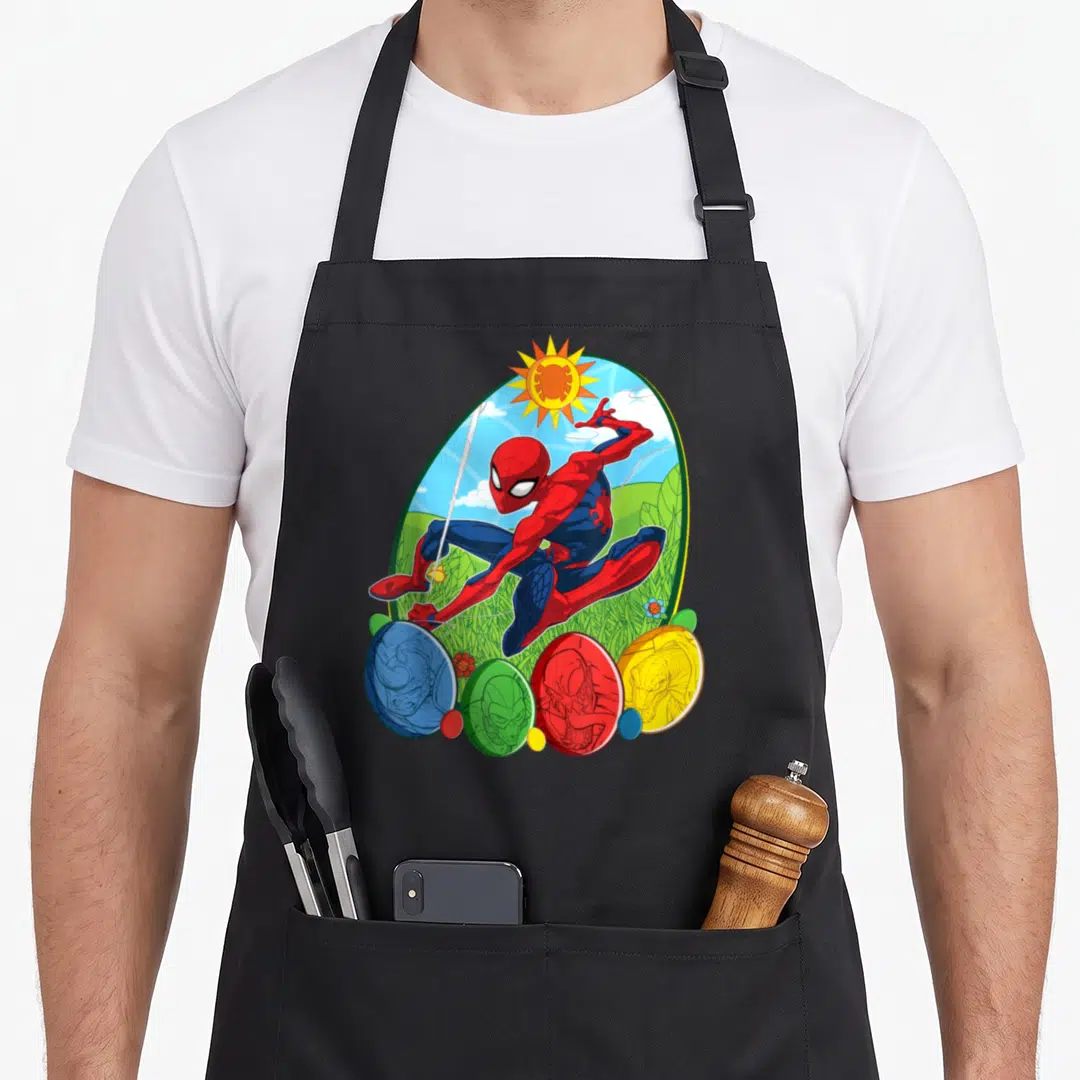 Villain egg apron - Spider-Man swinging above four colored eggs with villain faces in cartoon style — shown on a black cotton canvas apron against a white background