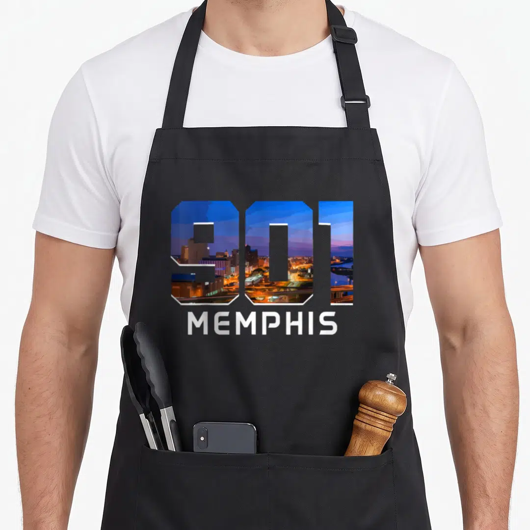 Code memphis apron - 901 numbers filled with blue and orange skyline above white MEMPHIS text — shown on a black cotton canvas apron against a white background