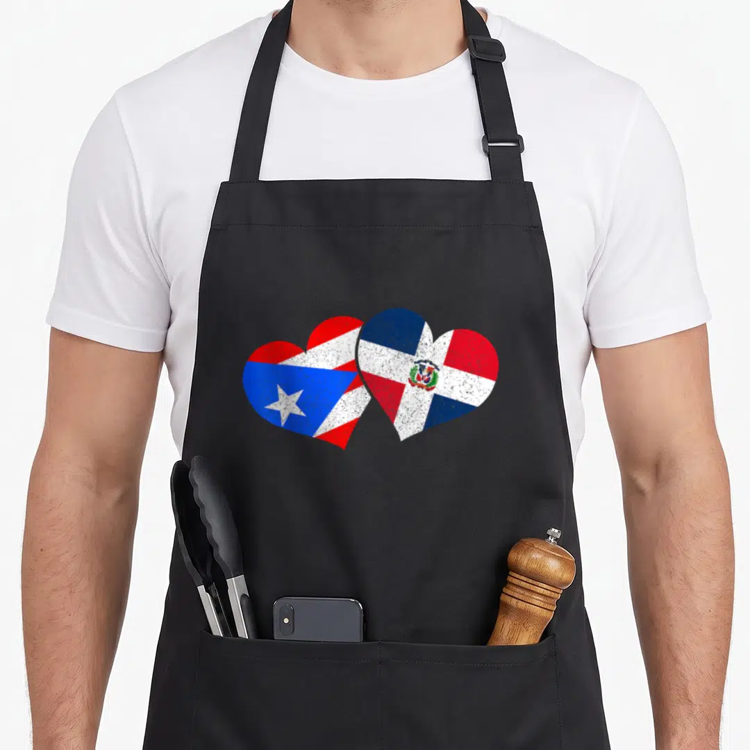 Rico dominican pride apron - Two overlapping hearts with Puerto Rican and Dominican flags in red white blue distressed — shown on a black cotton canvas apron against a white background
