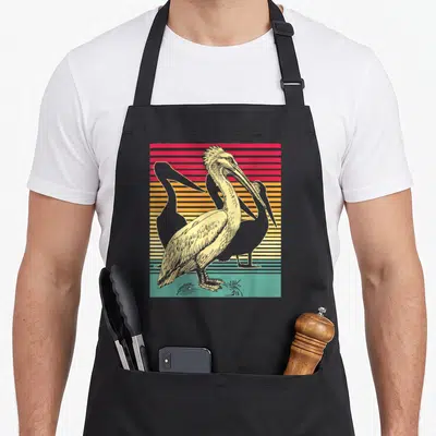 Pelican groomer apron - Retro pelican illustration on red orange yellow and green horizontal stripes — shown on a black cotton canvas apron against a white background