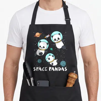 Space travel aprons - Three cartoon pandas in blue helmets floating near planets and rockets with white text below — shown on a black cotton canvas apron against a white background