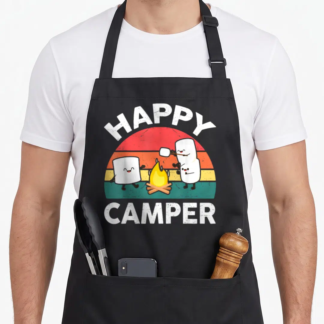 Toddler marshmallow camping apron - Happy Camper text above striped sun with three marshmallows and campfire — shown on a black cotton canvas apron against a white background