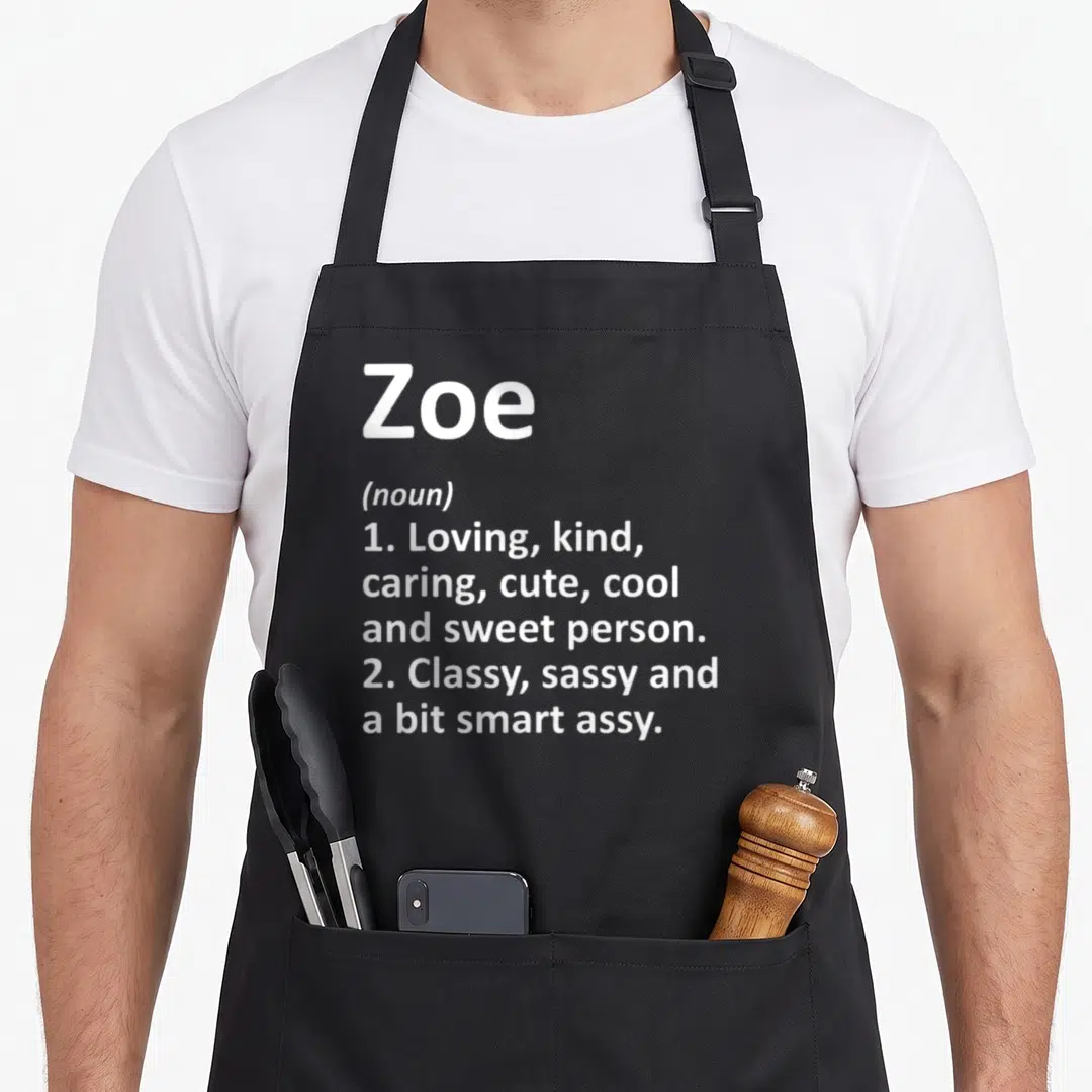 Zoe children's christmas apron - White text defining Zoe as a loving, kind, and sassy person on a gray background — shown on a black cotton canvas apron against a white background