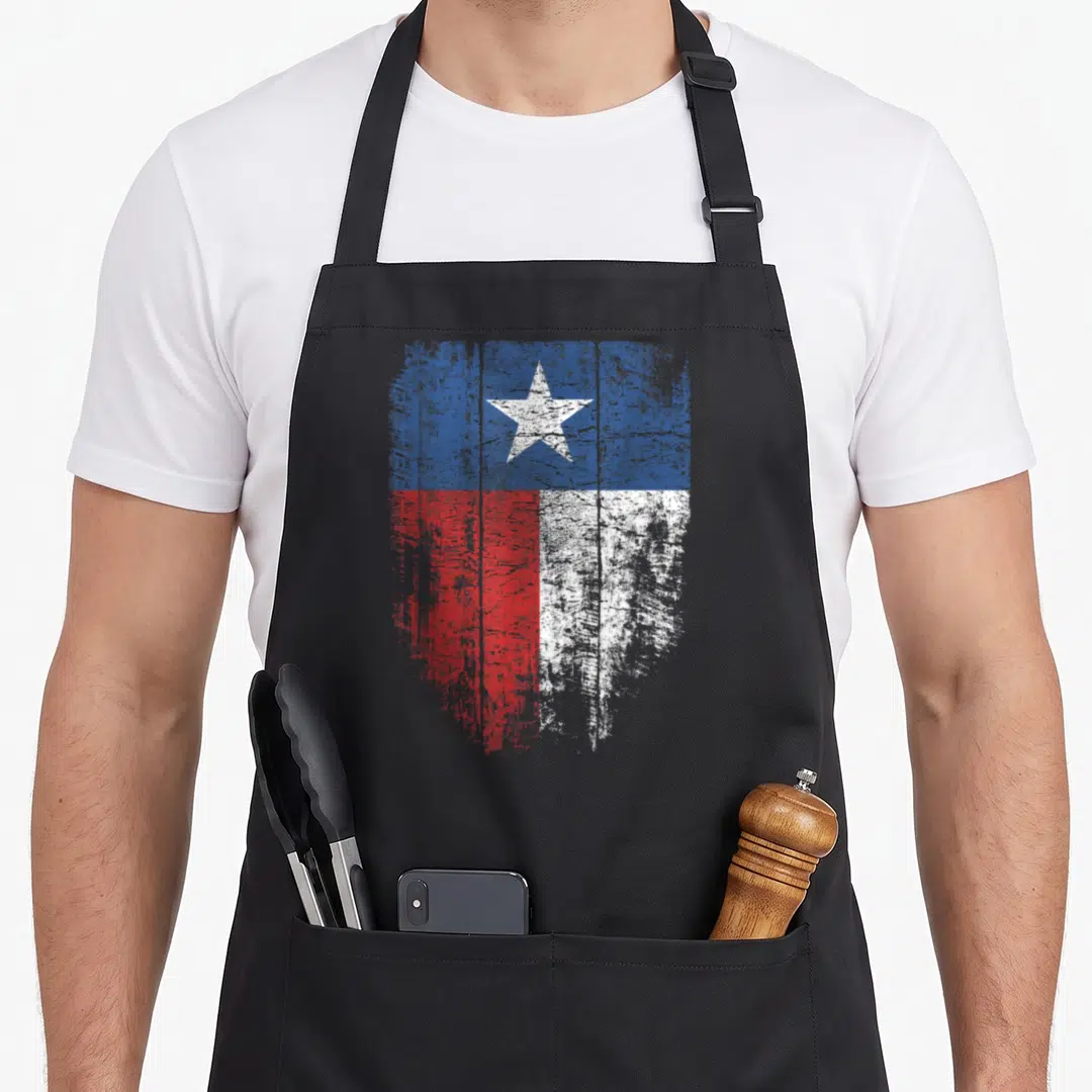 Distressed state texas apron - Distressed shield shaped Texas flag with lone star in blue red and white — shown on a black cotton canvas apron against a white background