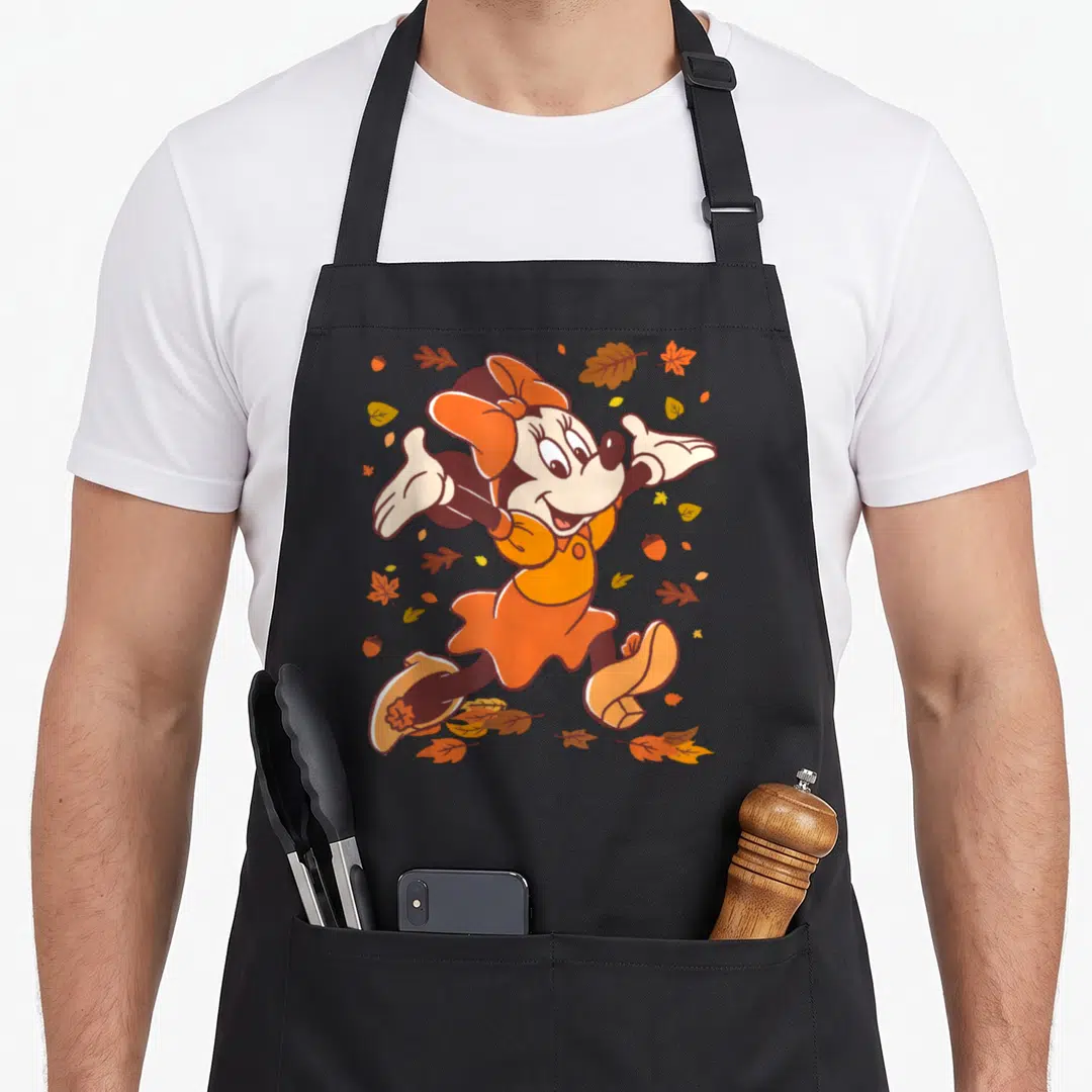 Strolling fall aprons - Cartoon mouse in orange dress surrounded by scattered brown and yellow autumn leaves and acorns — shown on a black cotton canvas apron against a white background