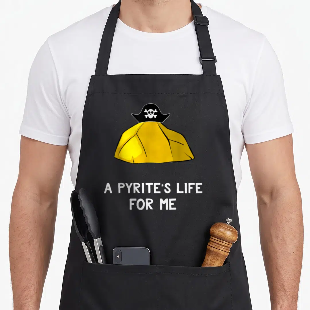 Pun geologist apron - Cartoon yellow pyrite wearing black pirate hat above white text A Pyrite's Life For Me — shown on a black cotton canvas apron against a white background