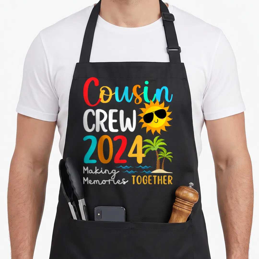 Crew summer family aprons - Cousin CREW 2024 Making Memories TOGETHER text with cartoon sun and palm trees — shown on a black cotton canvas apron against a white background