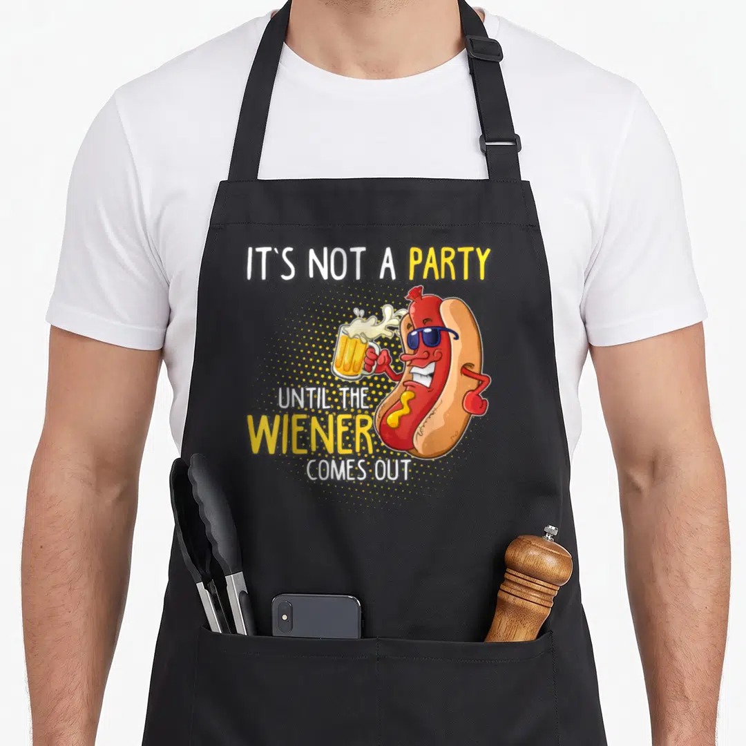 Come weiner apron - Cartoon hot dog wearing sunglasses holding a beer mug with party pun text — shown on a black cotton canvas apron against a white background