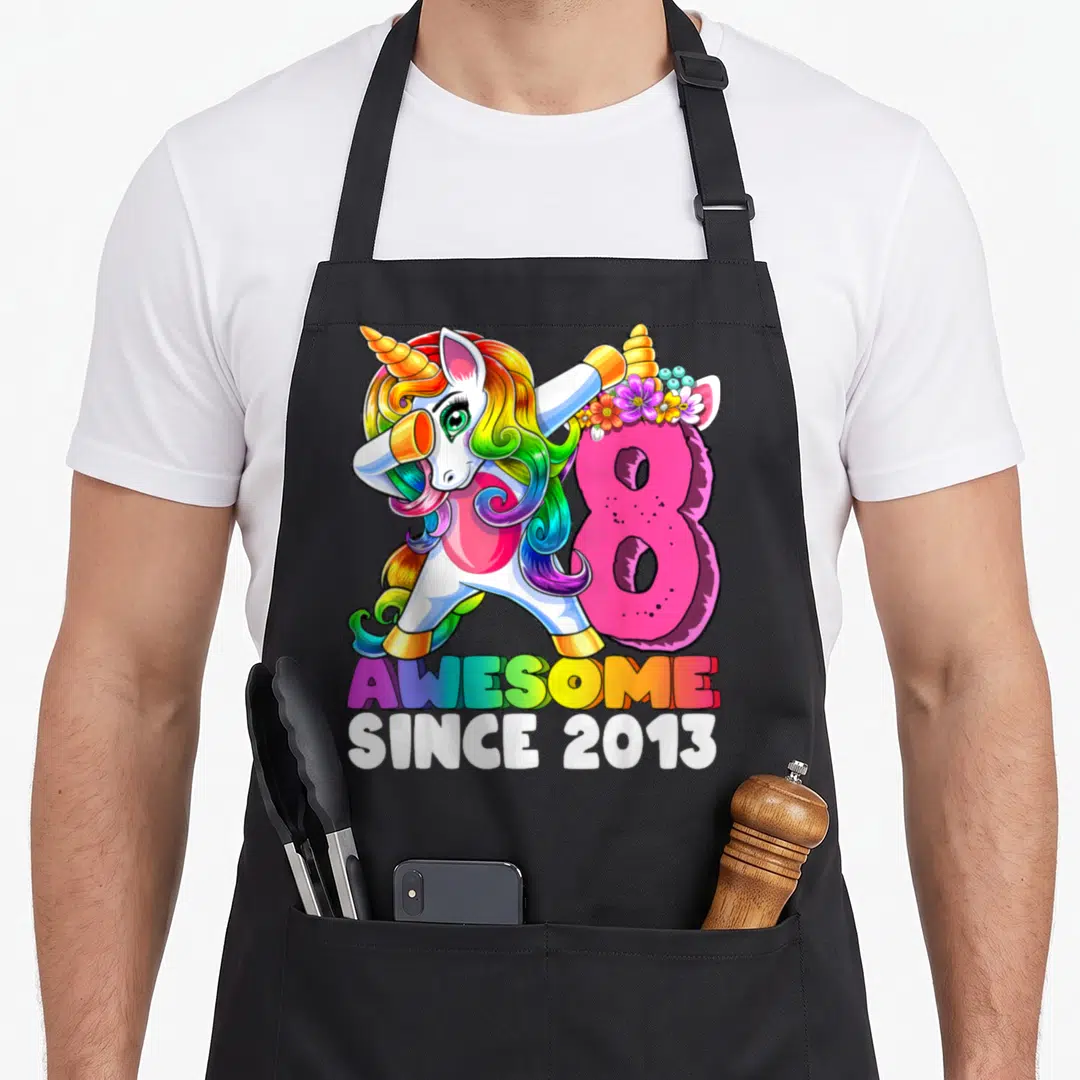 Unicorn birthday apron - Dabbing unicorn next to pink number 8 with flowers and rainbow text — shown on a black cotton canvas apron against a white background