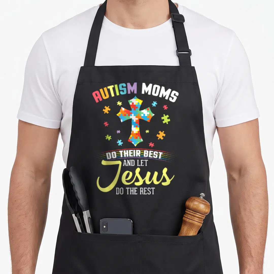 Autism christian apron - Multicolor puzzle cross with text Autism Moms Do Their Best And Let Jesus Do The Rest — shown on a black cotton canvas apron against a white background