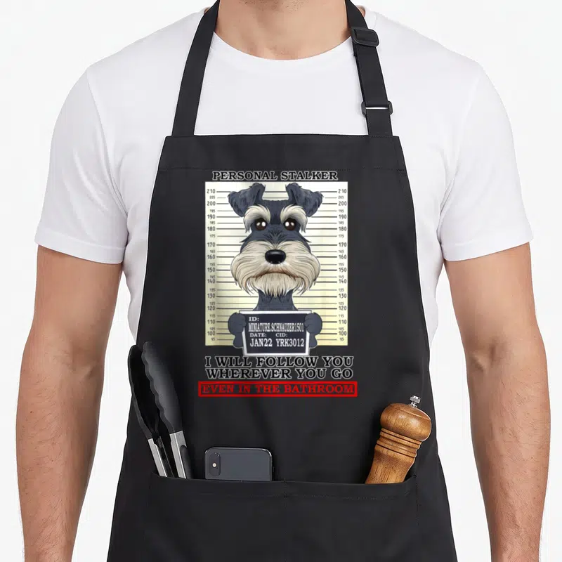 Personal miniature schnauzer apron - Cartoon Miniature Schnauzer mugshot holding ID sign with height chart and text — shown on a black cotton canvas apron against a white background