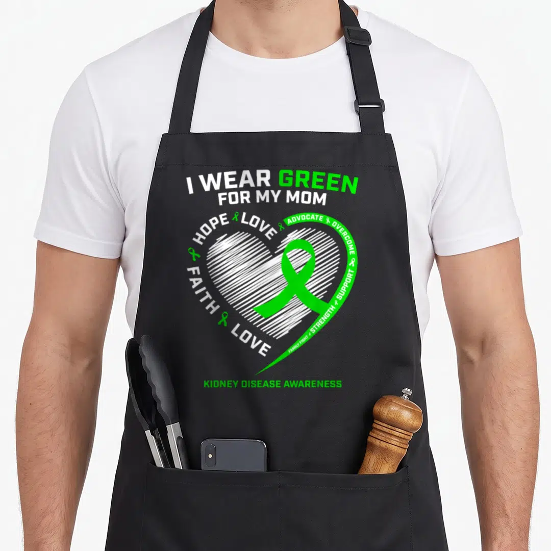 Fighter kidney disease awareness apron - Green ribbon inside white lined heart surrounded by advocacy text I wear green — shown on a black cotton canvas apron against a white background