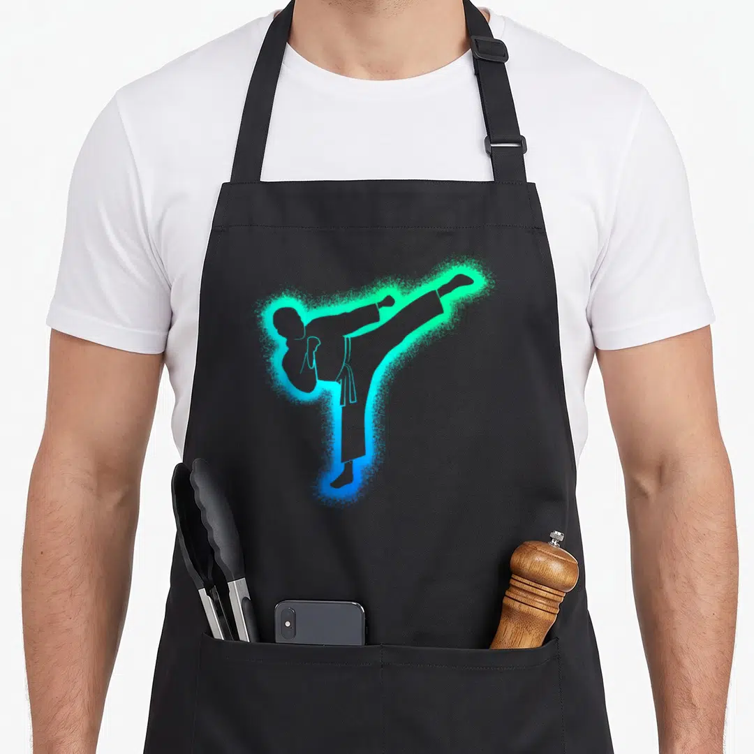 Taekwondo karate apron - Blue and green spray paint silhouette of a martial artist high kick — shown on a black cotton canvas apron against a white background