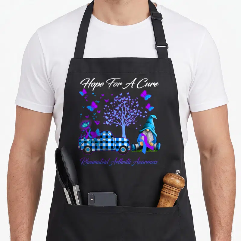 Hope rheumatoid arthritis awareness apron - Gnome holding purple ribbon next to blue plaid truck and butterfly tree — shown on a black cotton canvas apron against a white background