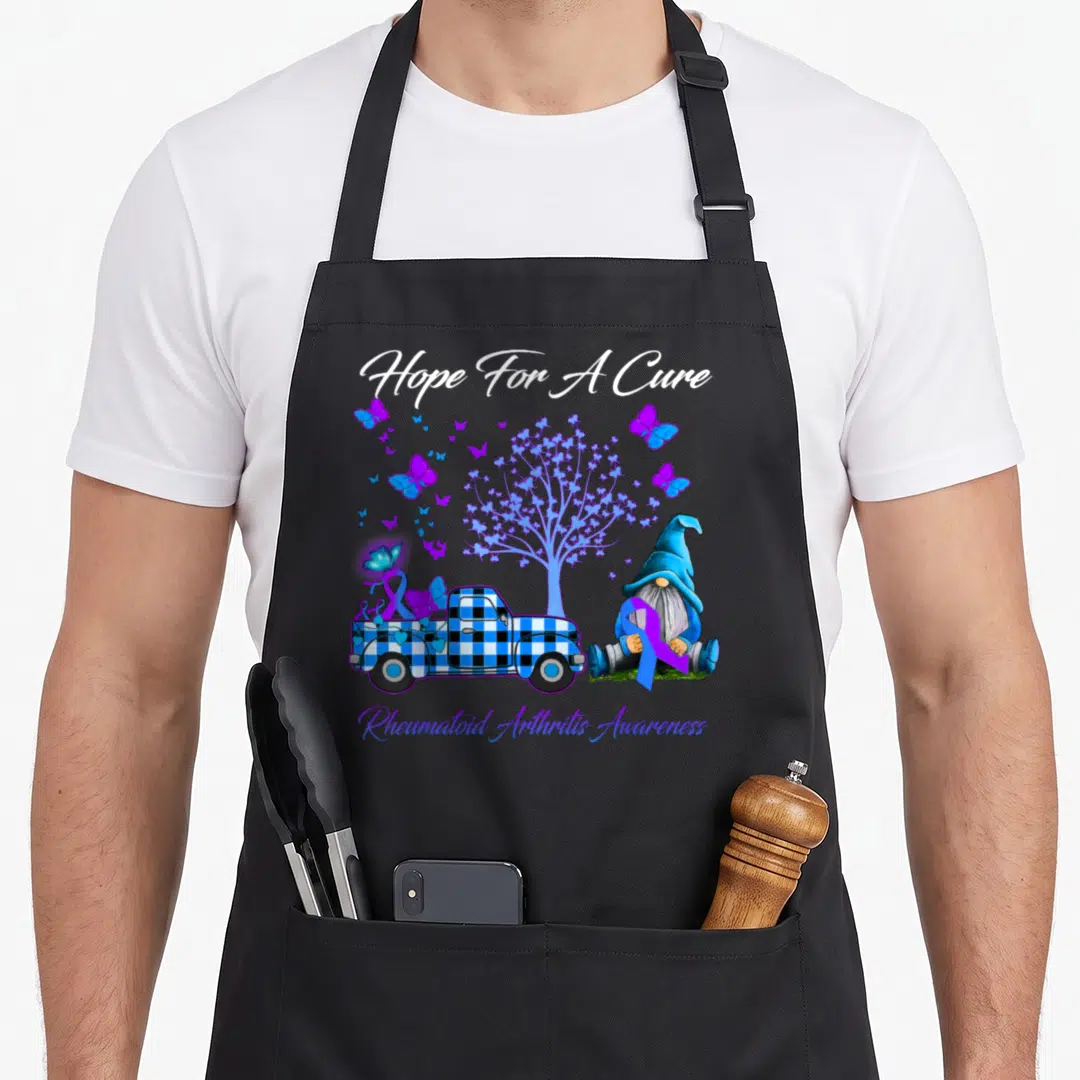 Hope rheumatoid arthritis awareness apron - Gnome holding purple ribbon next to blue plaid truck and butterfly tree — shown on a black cotton canvas apron against a white background