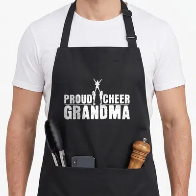 Cheerleader grandma apron - White PROUD CHEER GRANDMA text with three cheerleader silhouettes in a stunt — shown on a black cotton canvas apron against a white background