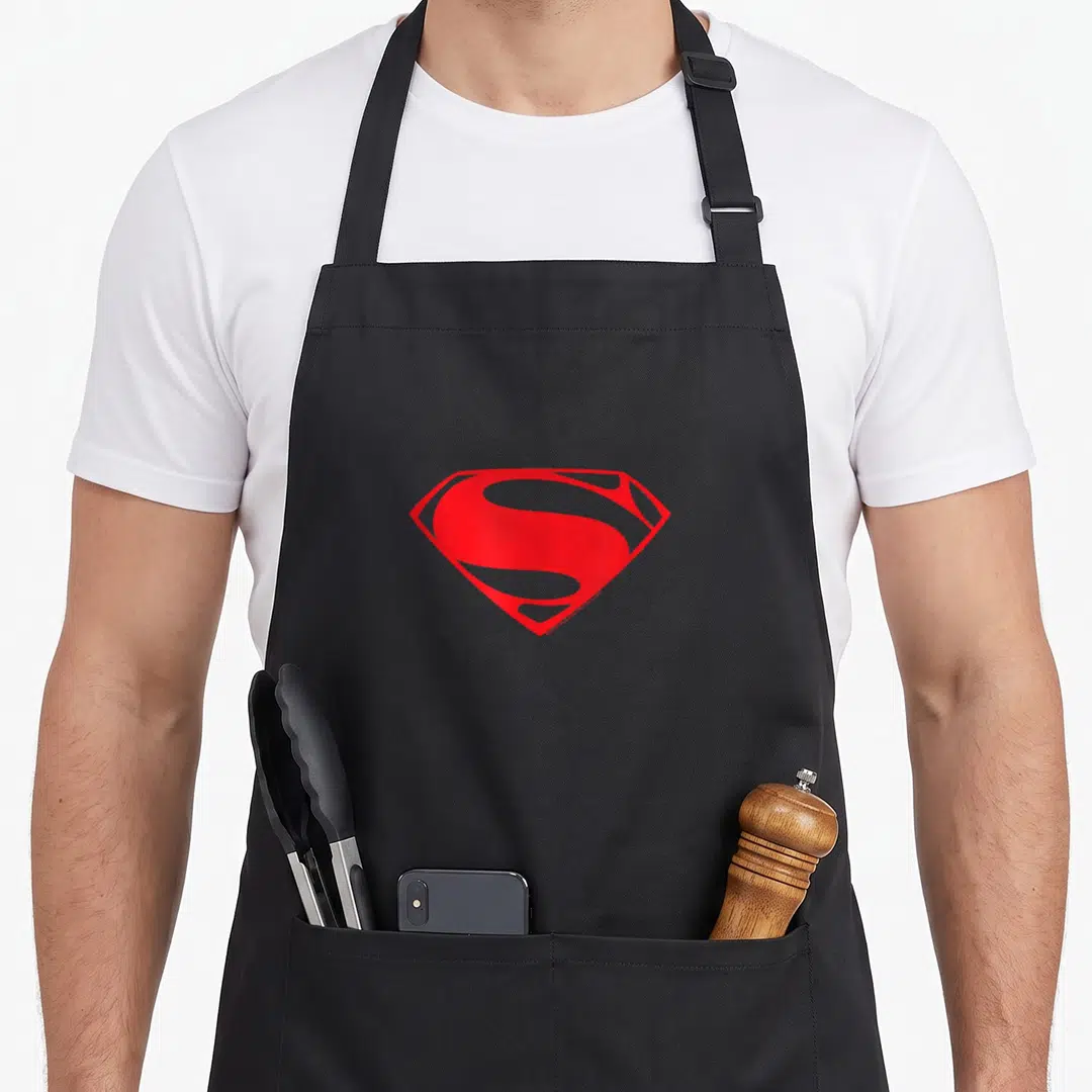 Steel current river apron - Red Superman shield logo centered on grey background — shown on a black cotton canvas apron against a white background
