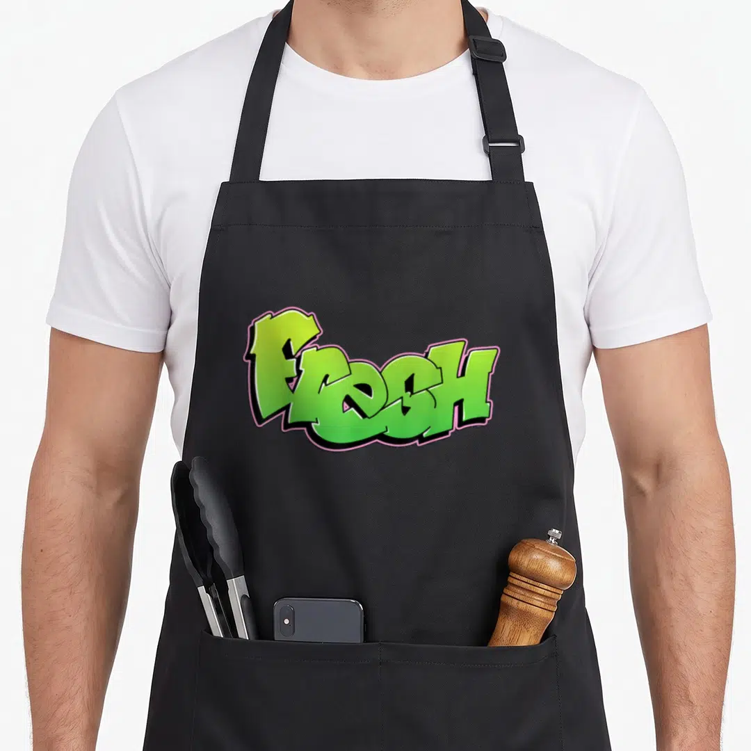 Fresh urban apron - Green graffiti word Fresh with pink and black outline, cartoon lettering — shown on a black cotton canvas apron against a white background