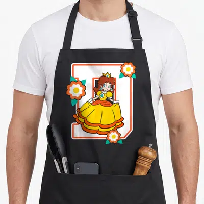 Poster daisy apron - Princess Daisy in yellow dress stands before orange letter D with three flowers — shown on a black cotton canvas apron against a white background