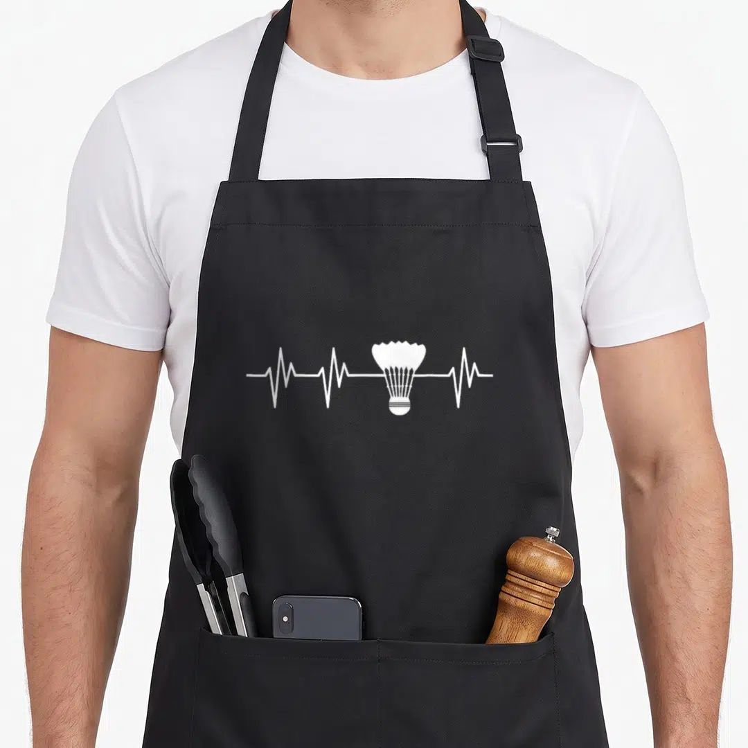 Heartbeat badminton apron - White shuttlecock centered on a horizontal heartbeat line in minimalist style — shown on a black cotton canvas apron against a white background