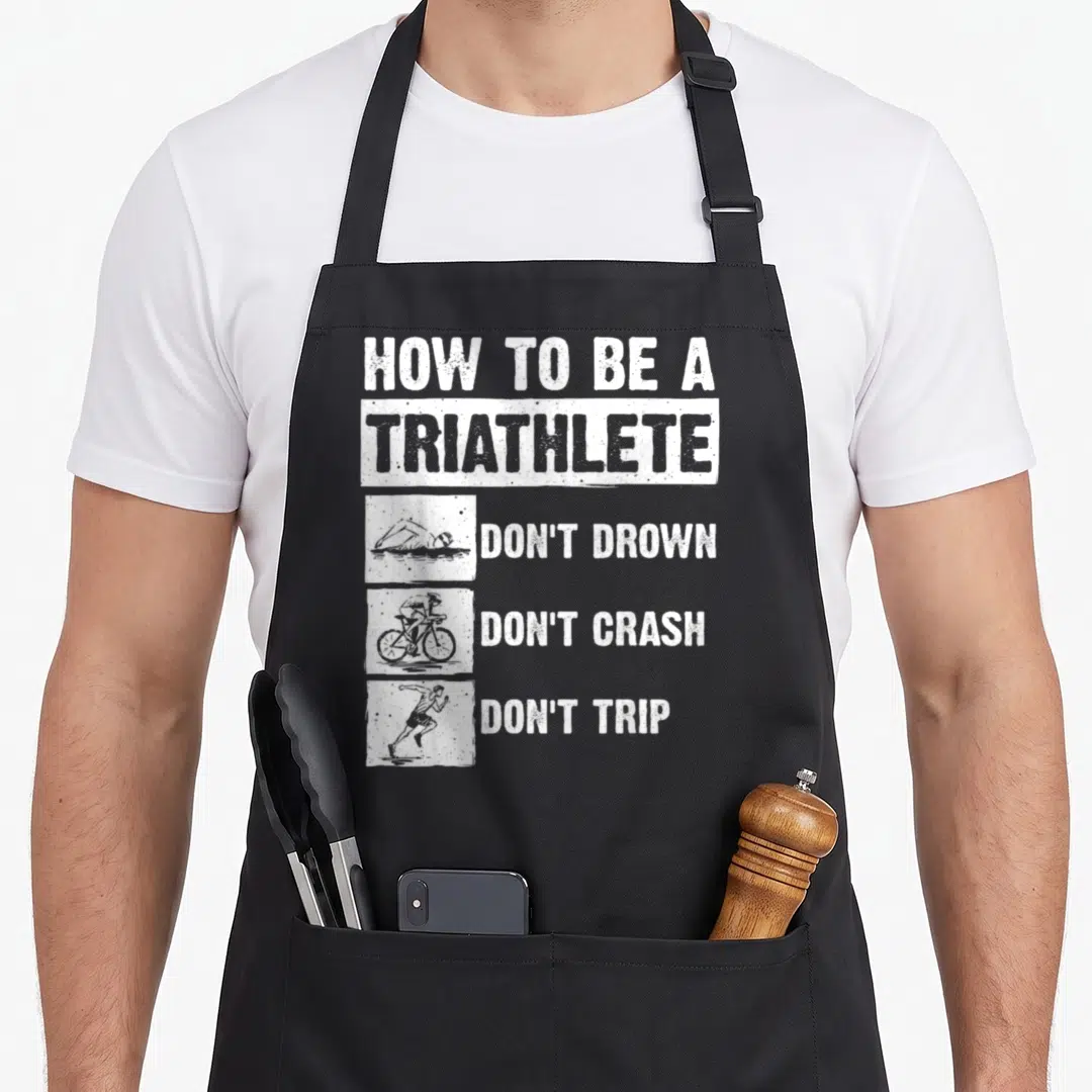 Triathlon swim bike apron - White distressed text reading Don't Drown Don't Crash Don't Trip above swim bike run — shown on a black cotton canvas apron against a white background