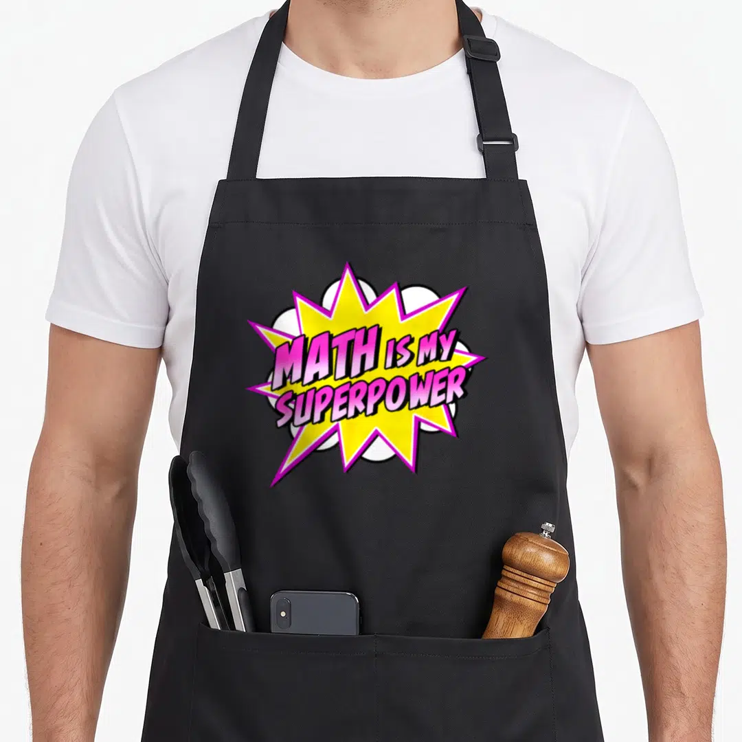Math superhero apron - MATH IS MY SUPERPOWER text in pink and white over a yellow comic burst — shown on a black cotton canvas apron against a white background