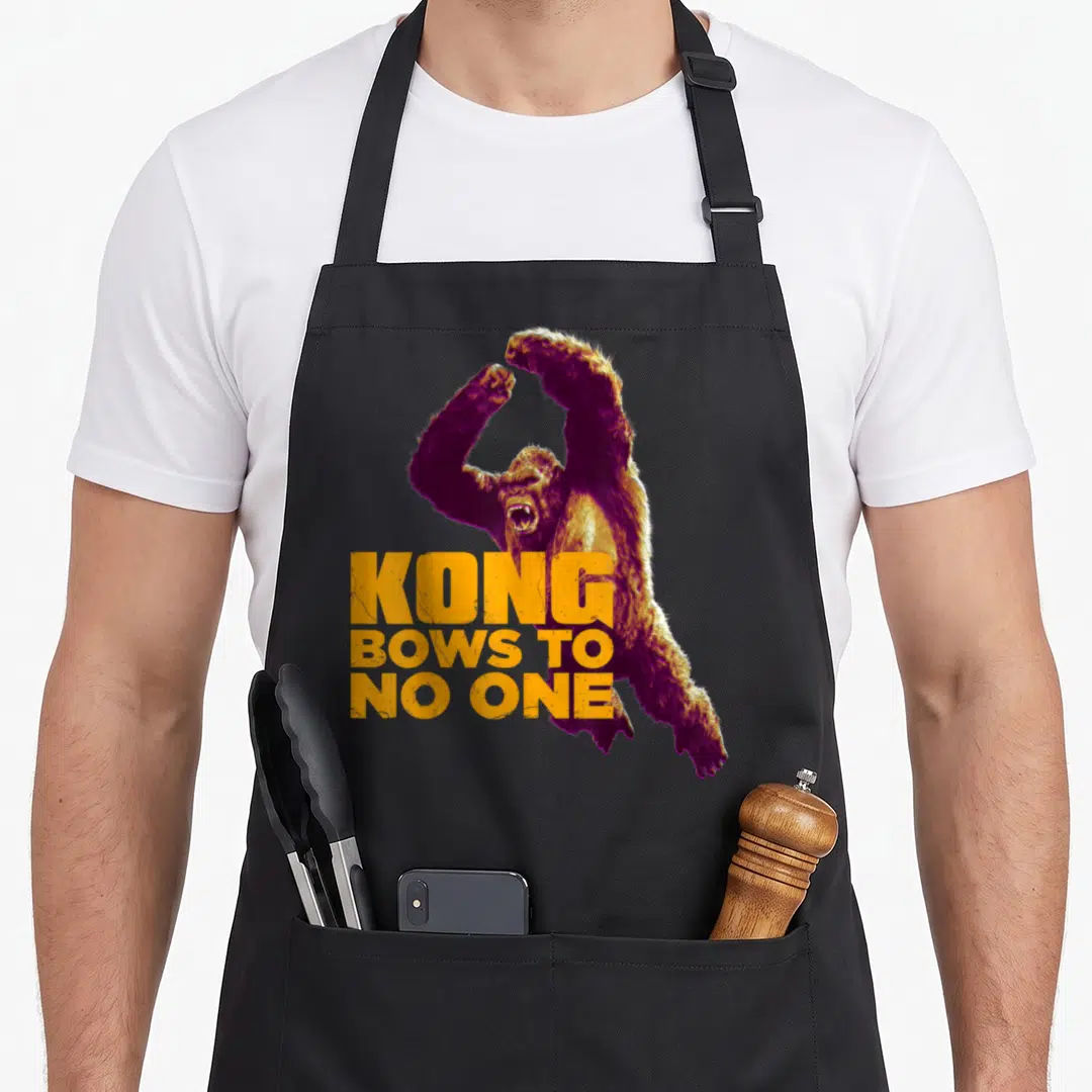 Kong bow apron - Realistic gorilla with raised arms and orange text reading KONG BOWS TO NO ONE — shown on a black cotton canvas apron against a white background