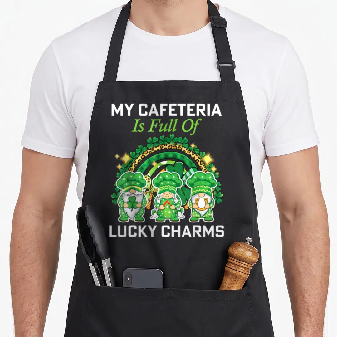 Patrick cafeteria aprons - Three gnomes in chef hats before a leopard and striped rainbow with shamrocks and stars — shown on a black cotton canvas apron against a white background