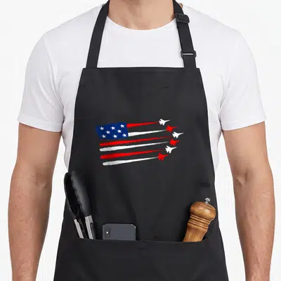 Fighter jet 4th of july apron - USA flag with red white blue smoke trails and five jets in cartoon style — shown on a black cotton canvas apron against a white background
