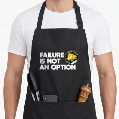 Option nasa apron - Failure Is Not An Option text next to Apollo 13 mission patch with yellow horses — shown on a black cotton canvas apron against a white background