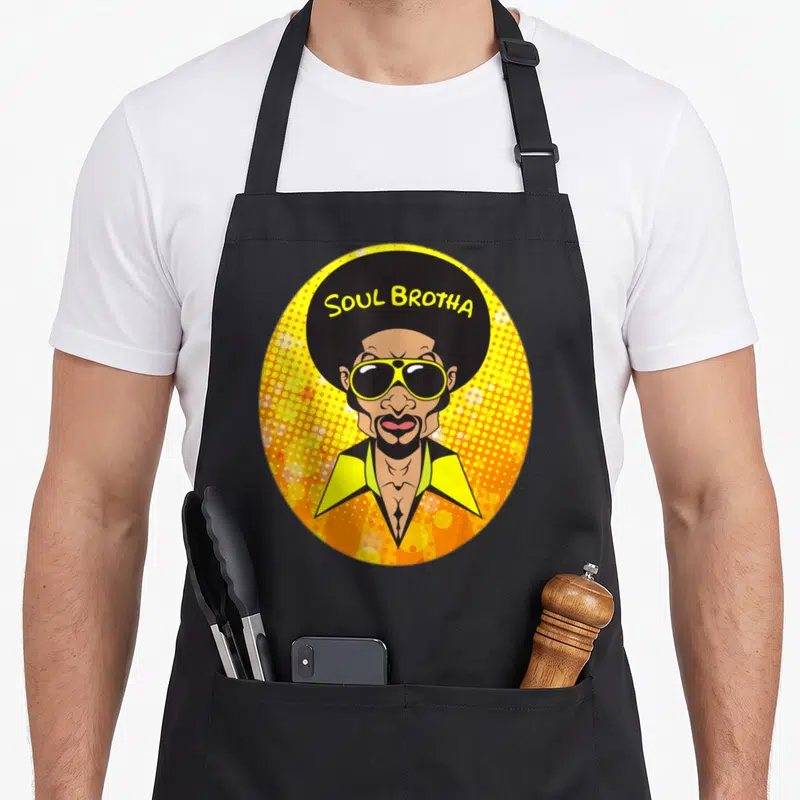 Rare 70s apron - Cartoon man with afro and sunglasses in yellow dotted circle with Soul Brotha text — shown on a black cotton canvas apron against a white background