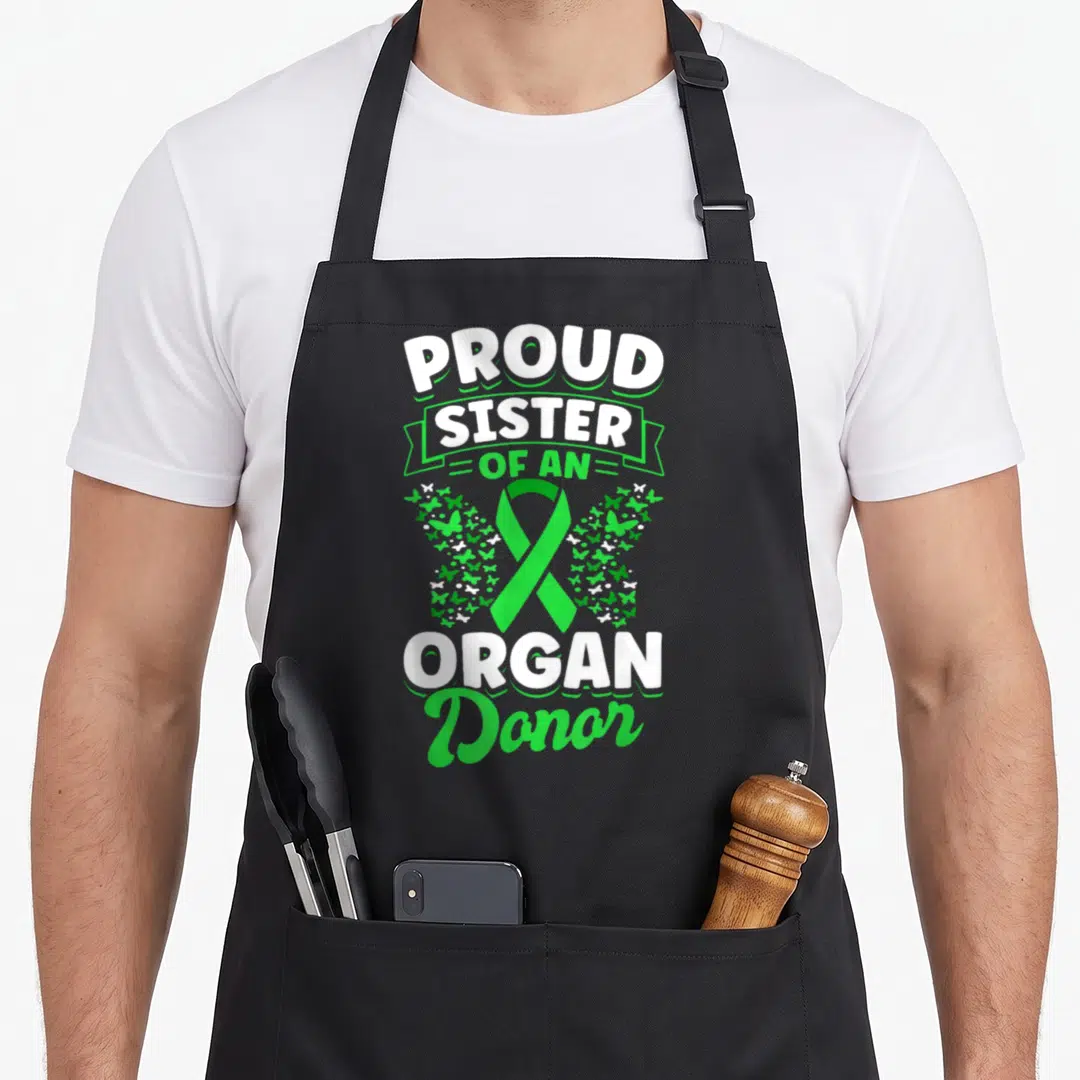 Proud organ apron - Green ribbon surrounded by butterflies with stacked white and green text reading PROUD SISTER — shown on a black cotton canvas apron against a white background