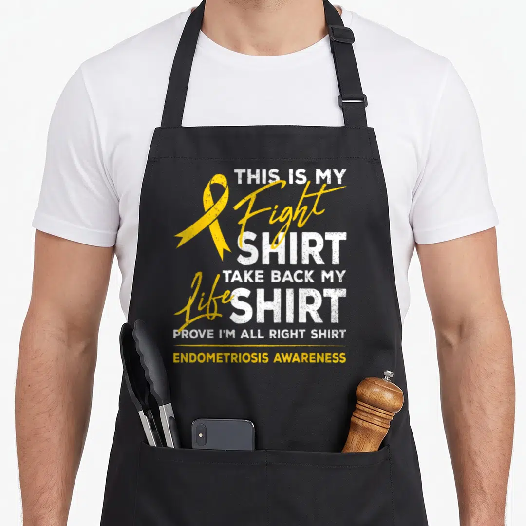 Endometriosis ribbon apron - Yellow awareness ribbon next to stacked white and yellow text reading THIS IS MY FIGHT — shown on a black cotton canvas apron against a white background