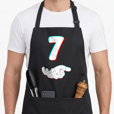 Six halloween apron - White number 7 and open hand with cyan and red glitch offset effect — shown on a black cotton canvas apron against a white background