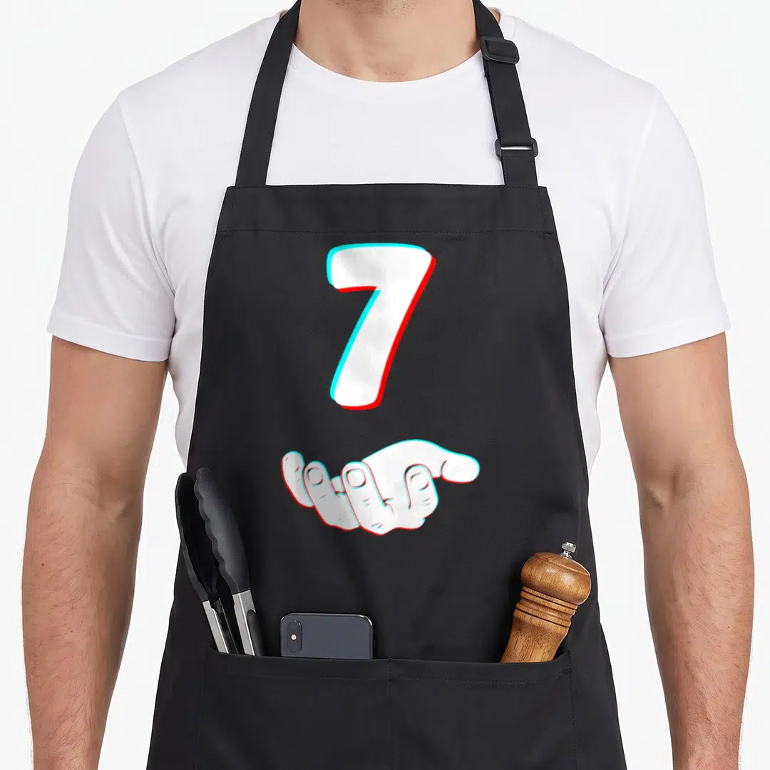Six halloween apron - White number 7 and open hand with cyan and red glitch offset effect — shown on a black cotton canvas apron against a white background