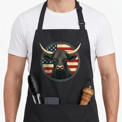 Cowboy rodeo western aprons - Realistic black bull head centered on circular red white and blue USA flag background — shown on a black cotton canvas apron against a white background