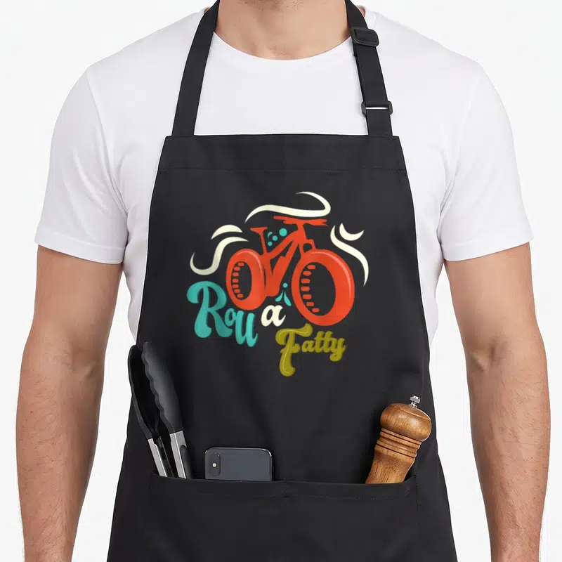 Roll meme apron - Red fat bike with white swirls and Roll a Fatty text in blue and olive green script — shown on a black cotton canvas apron against a white background