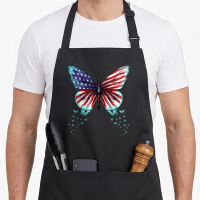 Flag butterfly apron - Large butterfly with red white and blue flag wings and smaller blue butterflies below — shown on a black cotton canvas apron against a white background