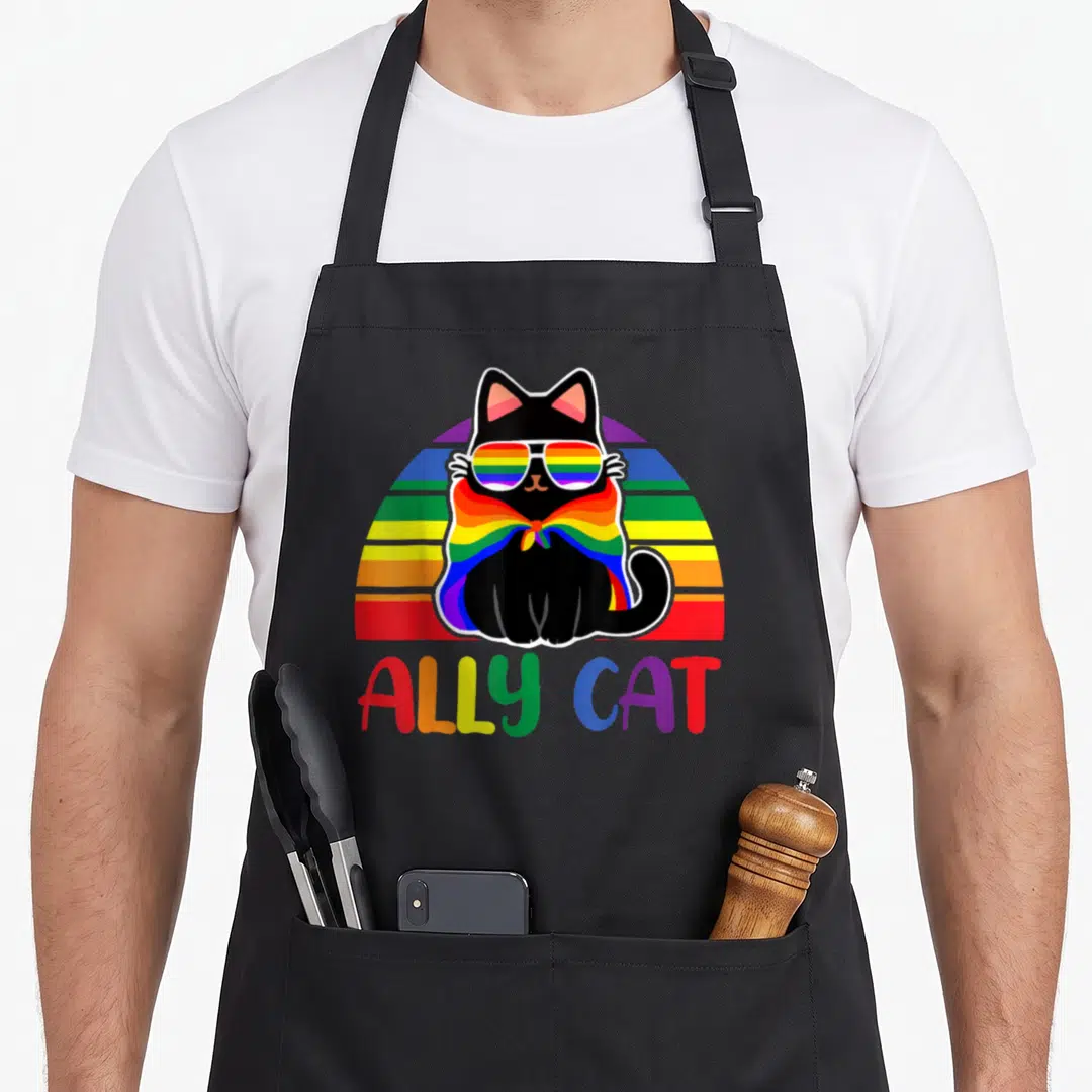 Ally cat gay pride apron - Black cat wearing rainbow sunglasses and scarf with ALLEY CAT text below — shown on a black cotton canvas apron against a white background