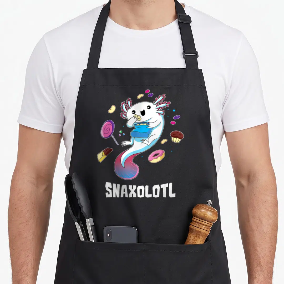 Snaxolotl cotton candy apron - Cartoon axolotl holding blue snack bag surrounded by sweets and white text — shown on a black cotton canvas apron against a white background