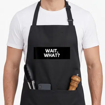 Wait popular aprons - White stacked WAIT, WHAT? text on black fabric — shown on a black cotton canvas apron against a white background