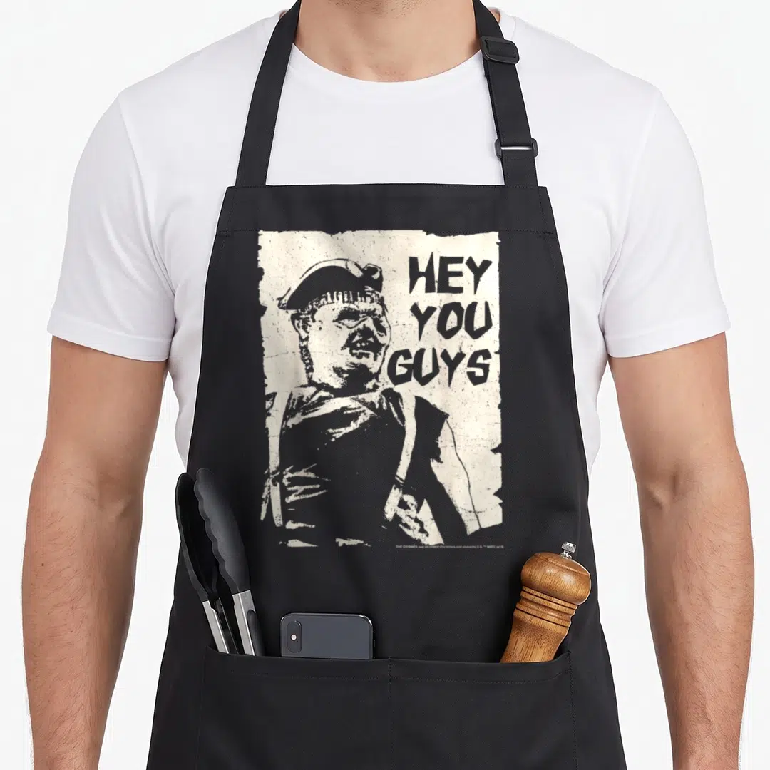 Hey sloth apron - Distressed beige rectangle with grey character portrait and stacked HEY YOU GUYS text — shown on a black cotton canvas apron against a white background