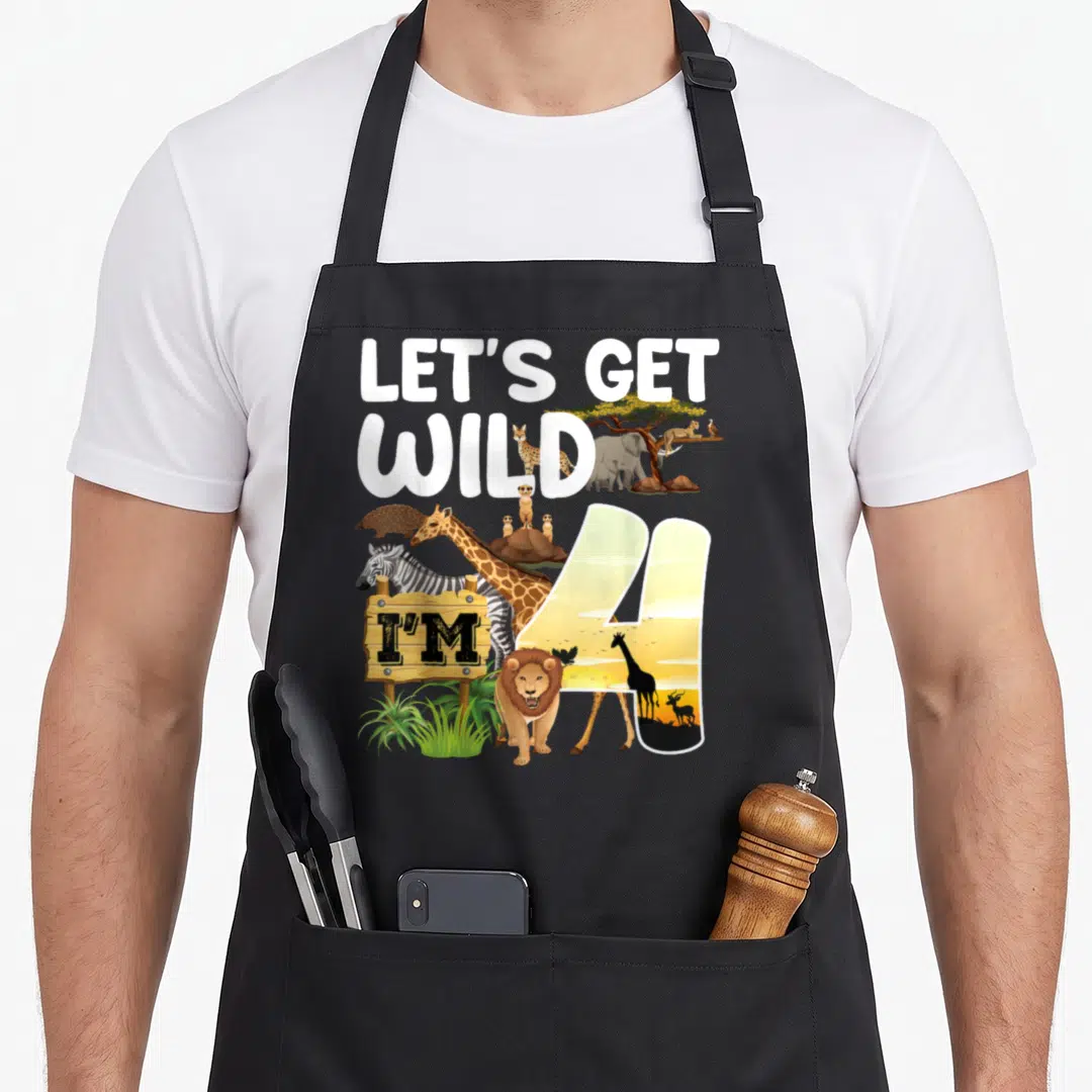 Animal 4th birthday apron - White LET'S GET WILD text above a sunset-filled number 4 with cartoon giraffes, zebras — shown on a black cotton canvas apron against a white background