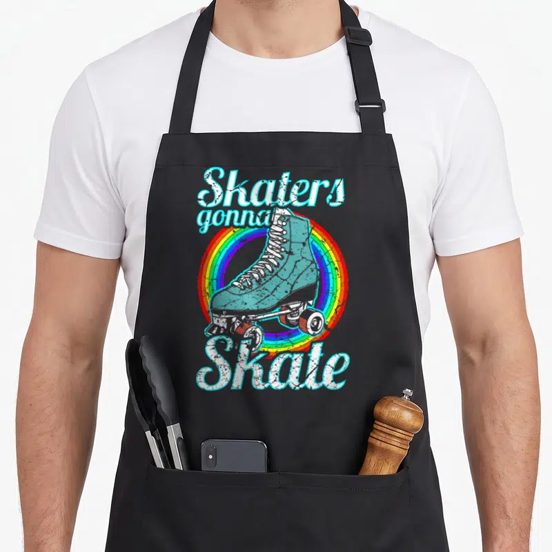 Skater disco seventies apron - Retro blue roller skate on rainbow circle with white arched text reading Skaters gonna — shown on a black cotton canvas apron against a white background