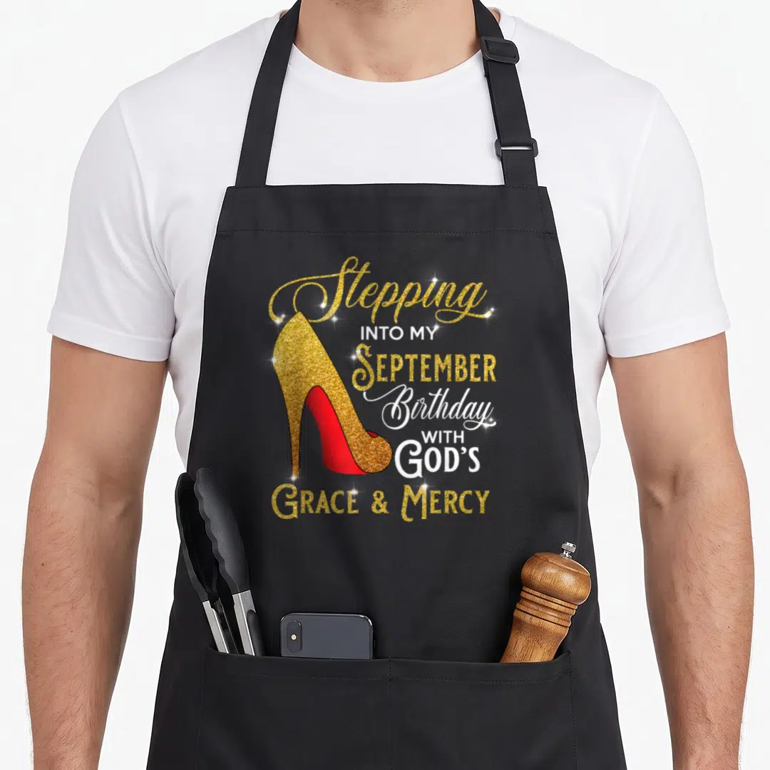 September grace apron - Gold glitter high heel shoe with red sole and stacked birthday faith typography — shown on a black cotton canvas apron against a white background