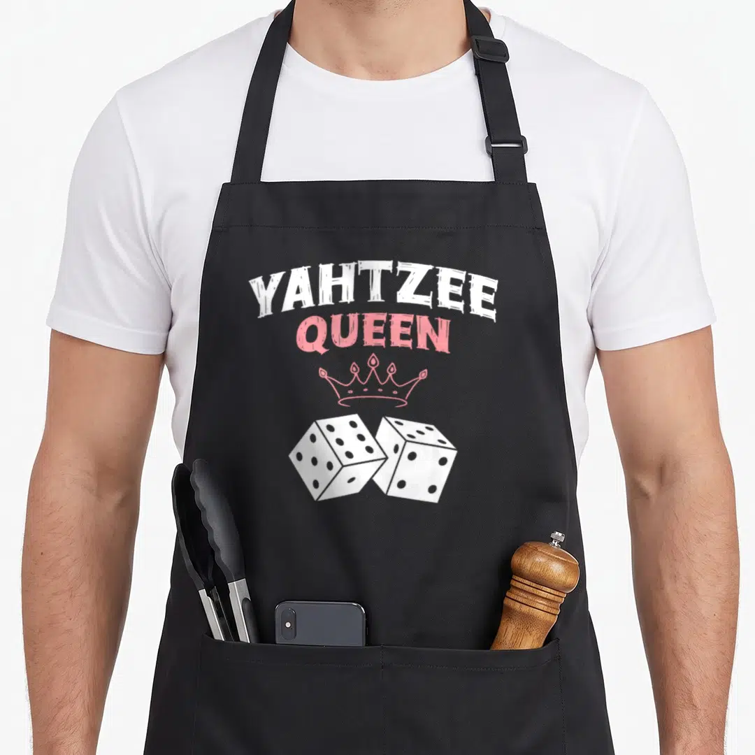 Yahtzee queen apron - White and pink distressed YAHTZEE QUEEN text with crown and two dice — shown on a black cotton canvas apron against a white background