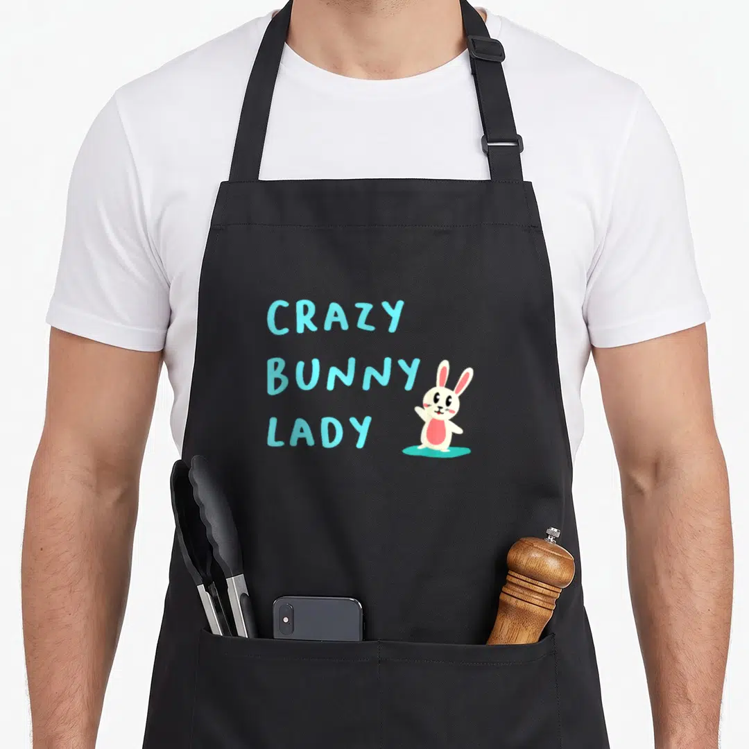 Cute animal bunny apron - Stacked cyan text reading CRAZY BUNNY LADY beside a white cartoon rabbit with pink ears — shown on a black cotton canvas apron against a white background